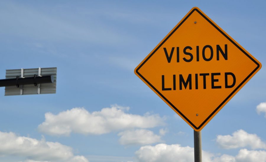 Vision limited yellow road sign and traffic lights, with blue sky white clouds in background