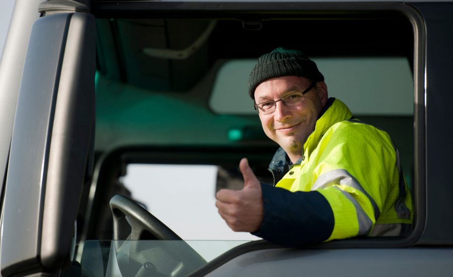 Truck driver wearing reflective jacket smiling and giving thumbs up