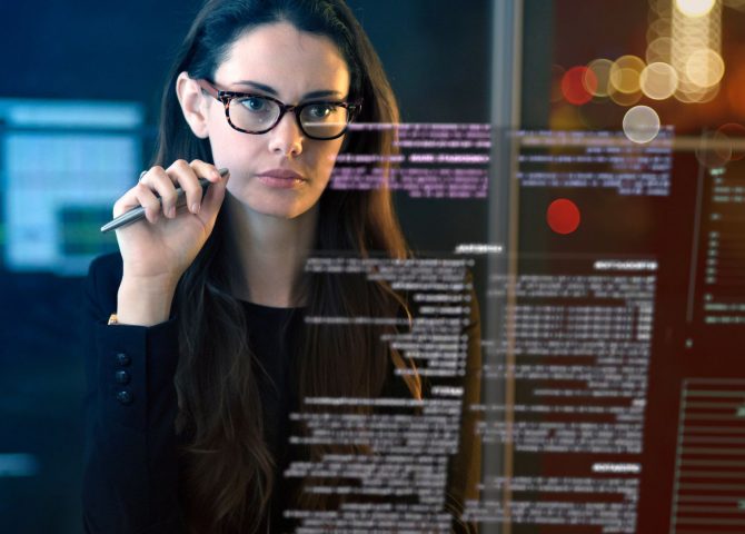 business woman looking at glass screen with computer data and text displayed on it